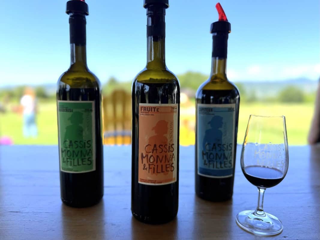 Bottles of cassis wine displayed outdoors with the St. Lawrence River in the background.