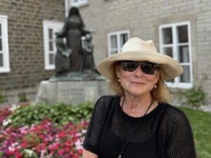 Author Sharon Kurtz stands beside the statue of Saint Marie de l’Incarnation at the Ursuline School.