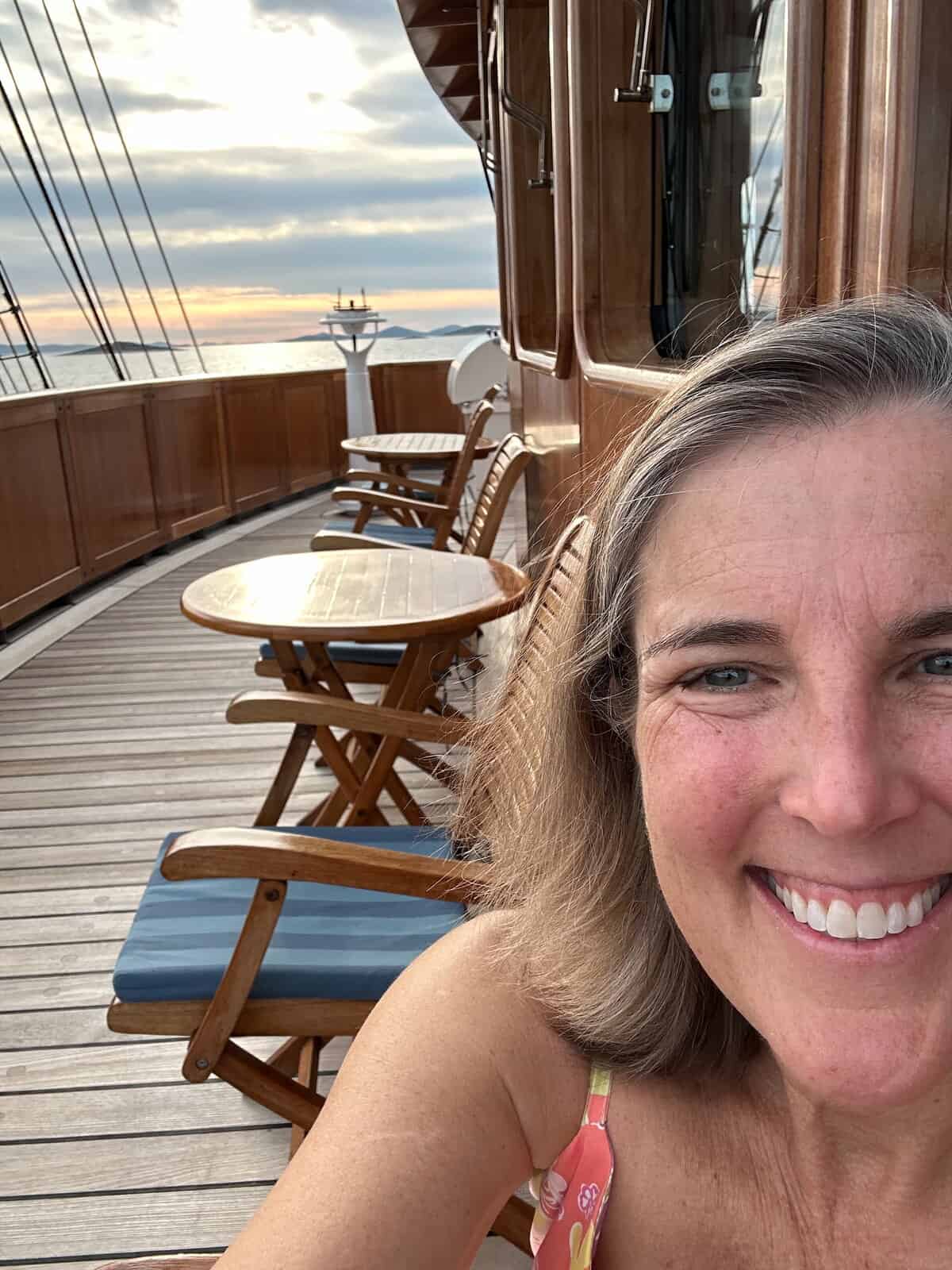 Author standing at the bow of a sailing ship with ocean and rigging visible.