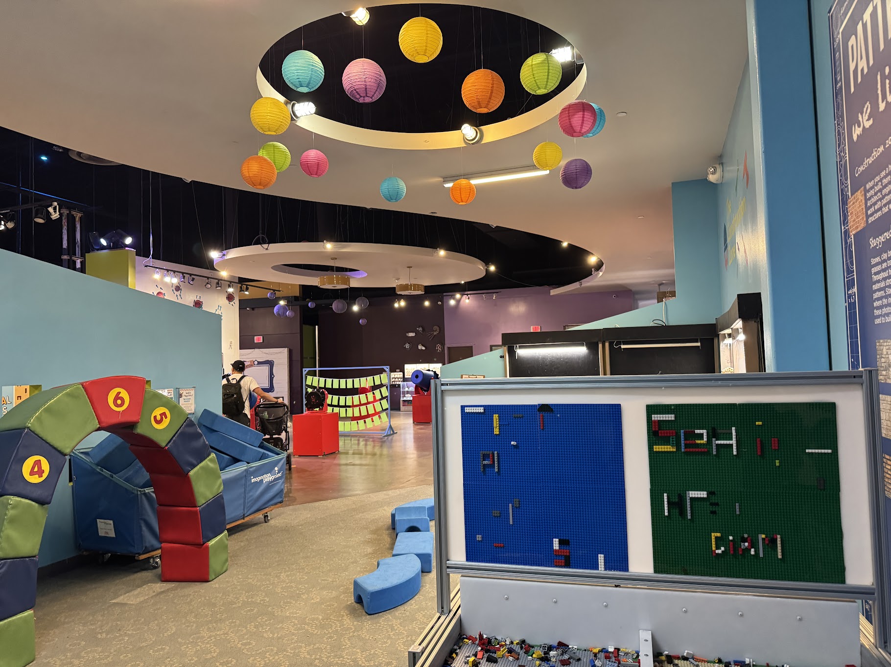 Several learning stations with blocks and Lego-like pieces, with a model of planets hanging from the ceiling.