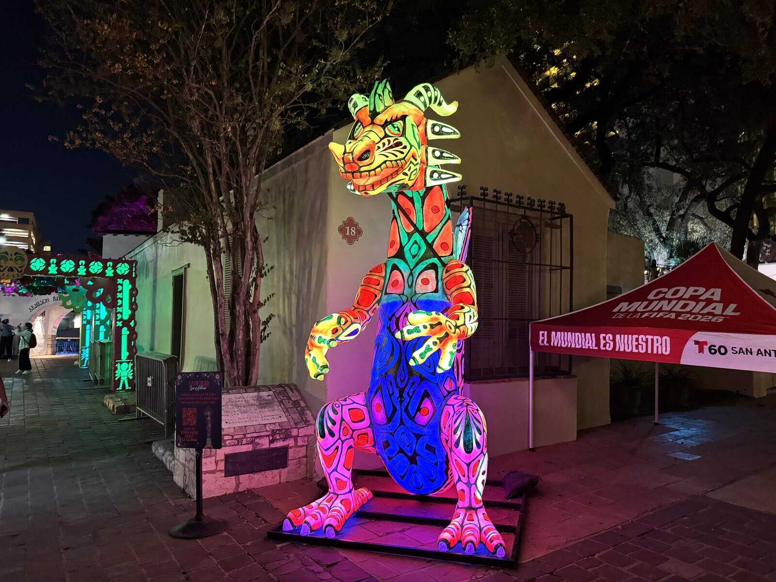 A multi-colored dragon is lit up during a nighttime setting.