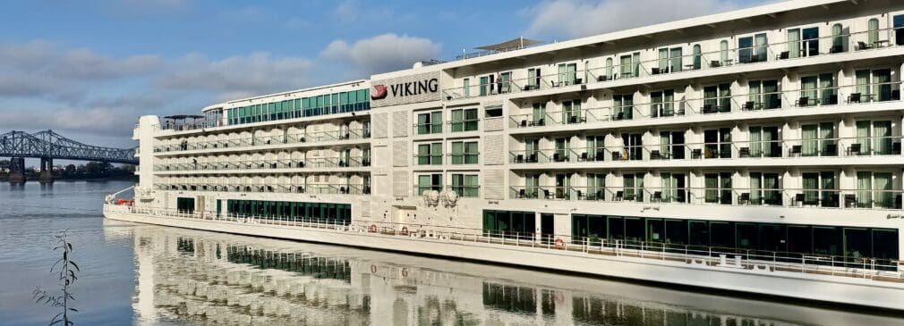 5-deck tall river boat on the river with a bridge in the background