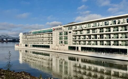 5-deck tall river boat on the river with a bridge in the background