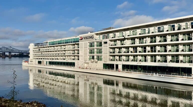 5-deck tall river boat on the river with a bridge in the background