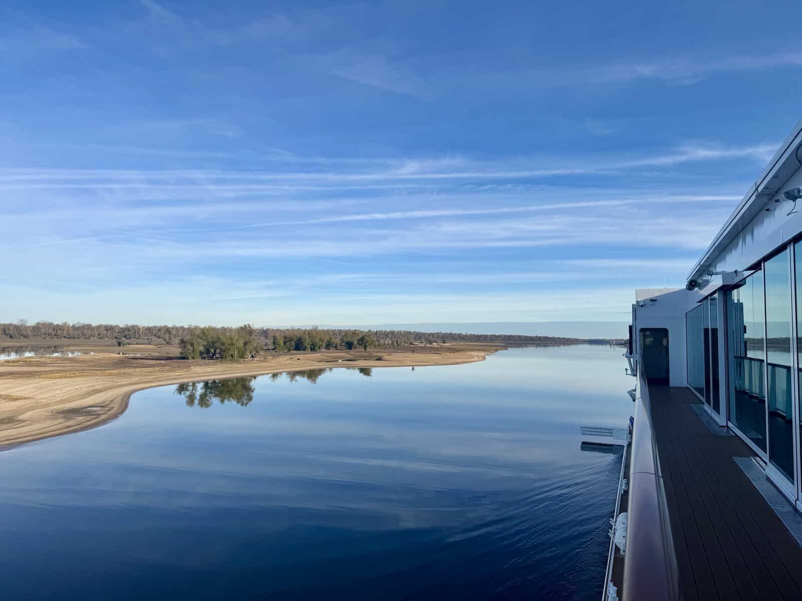 View of the river and sand dunes dotted with trees from the ship.
