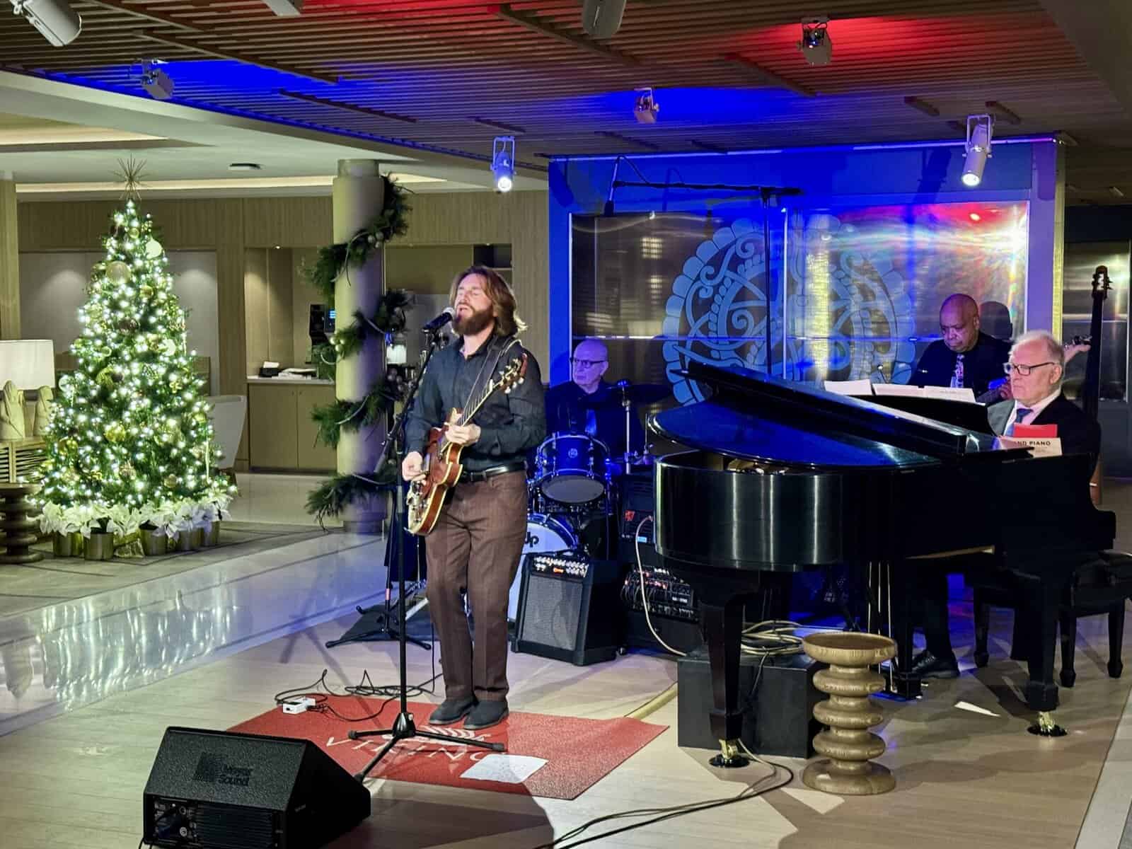 Man plays the bass guitar and sings while accompanied by a 3-piece band.