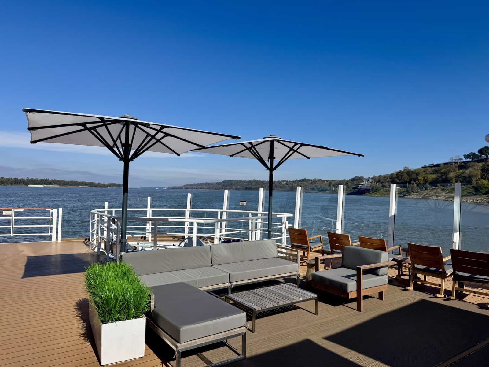 Chairs on the deck of the ship, with a view of the river beyond.