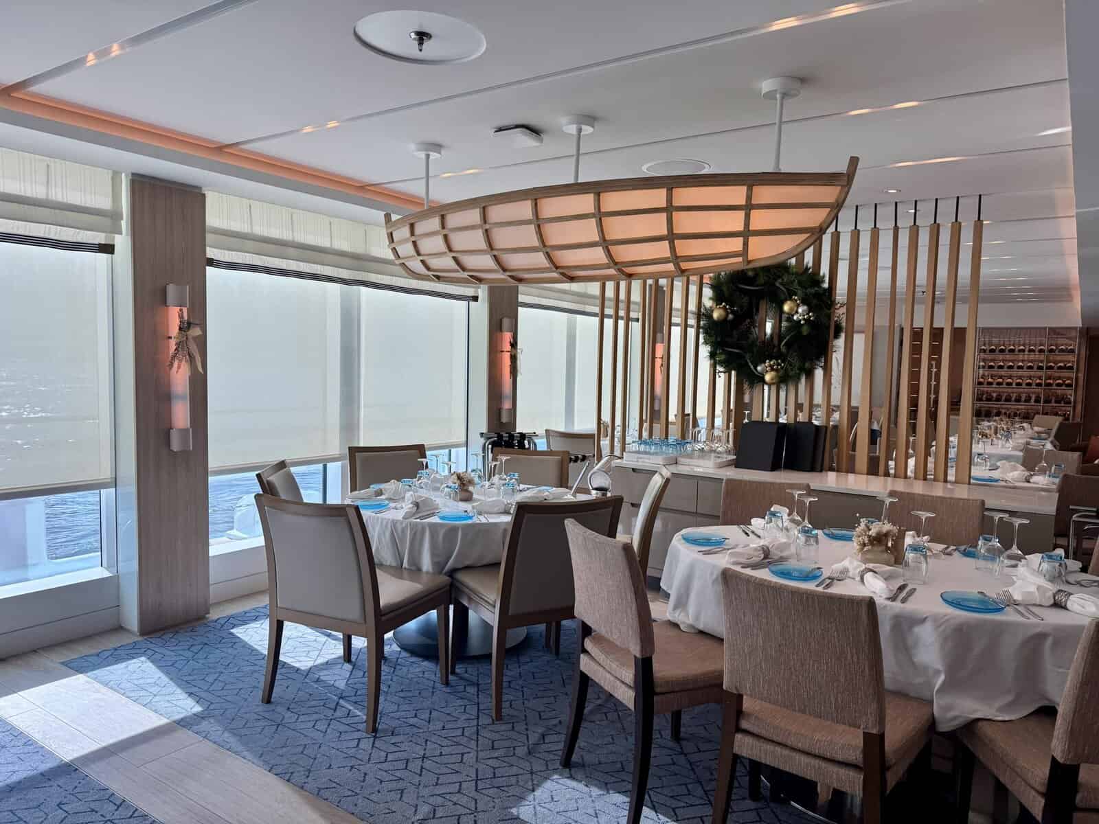 Tables set with blue plates under a canoe-shaped light.