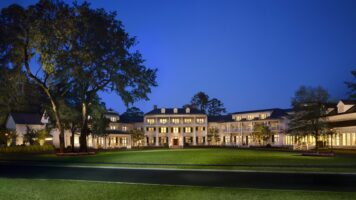 Inn exterior at night with white colonial architecture and oak trees at Montage Palmetto Bluff.