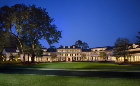 Inn exterior at night with white colonial architecture and oak trees at Montage Palmetto Bluff.