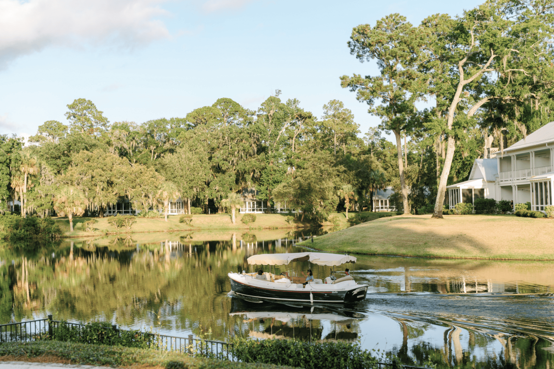 Boat on waterway with Spanish moss trees and cottages at Montage Palmetto Bluff.