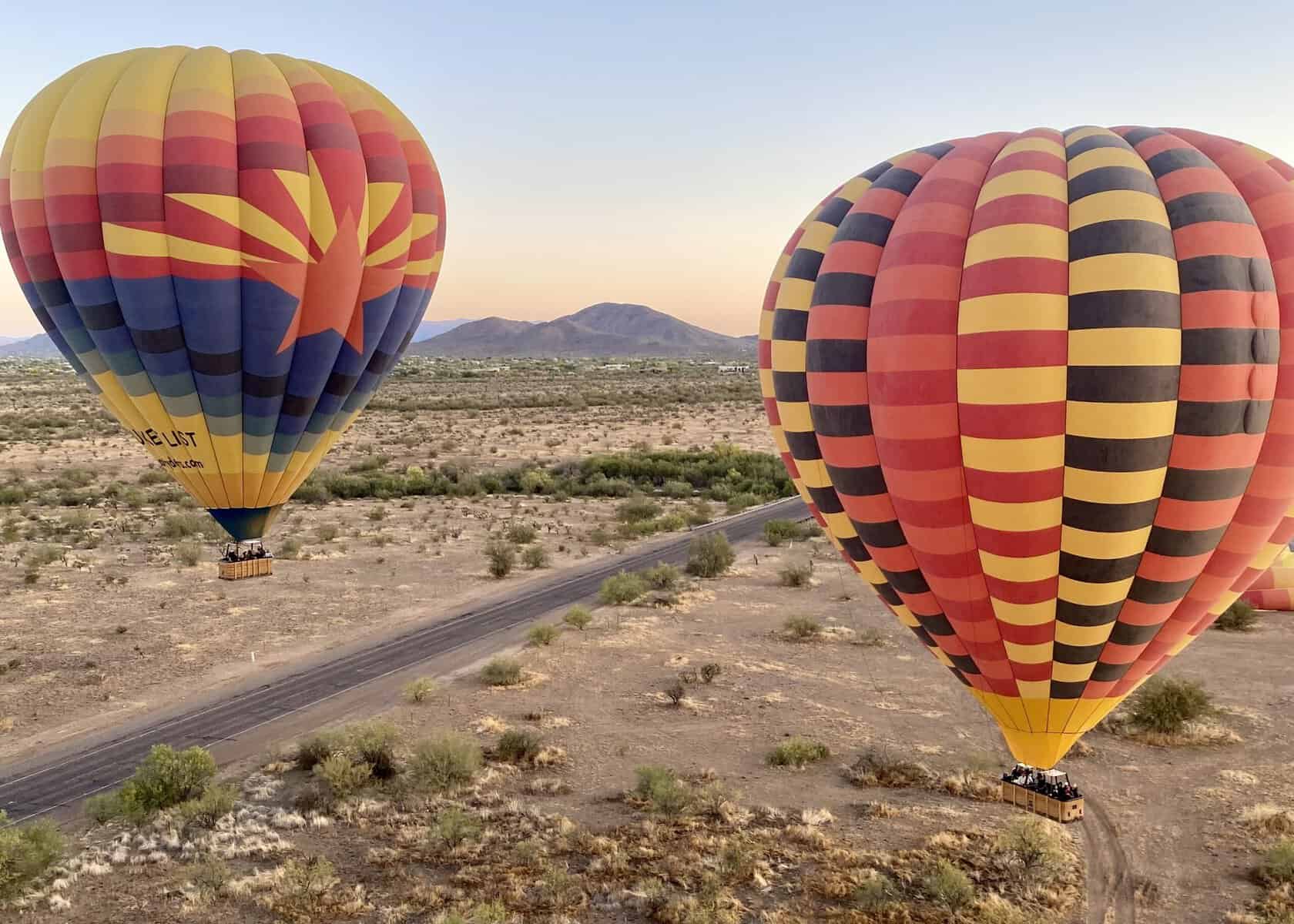 two hot air balloons fly toward mountains