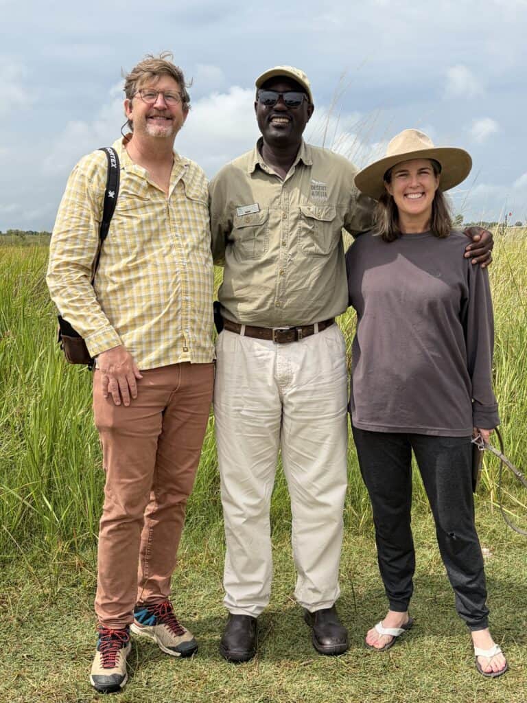 Three people standing together in grassland during Botswana safari.