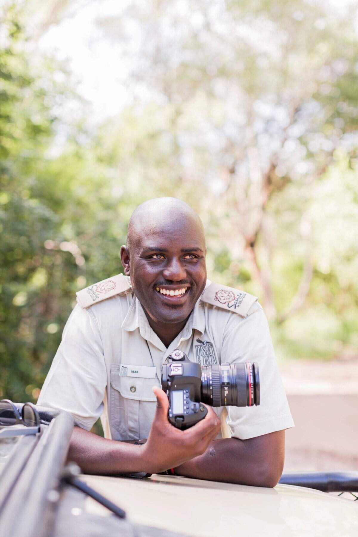 Safari guide holding camera in safari vehicle in Botswana.