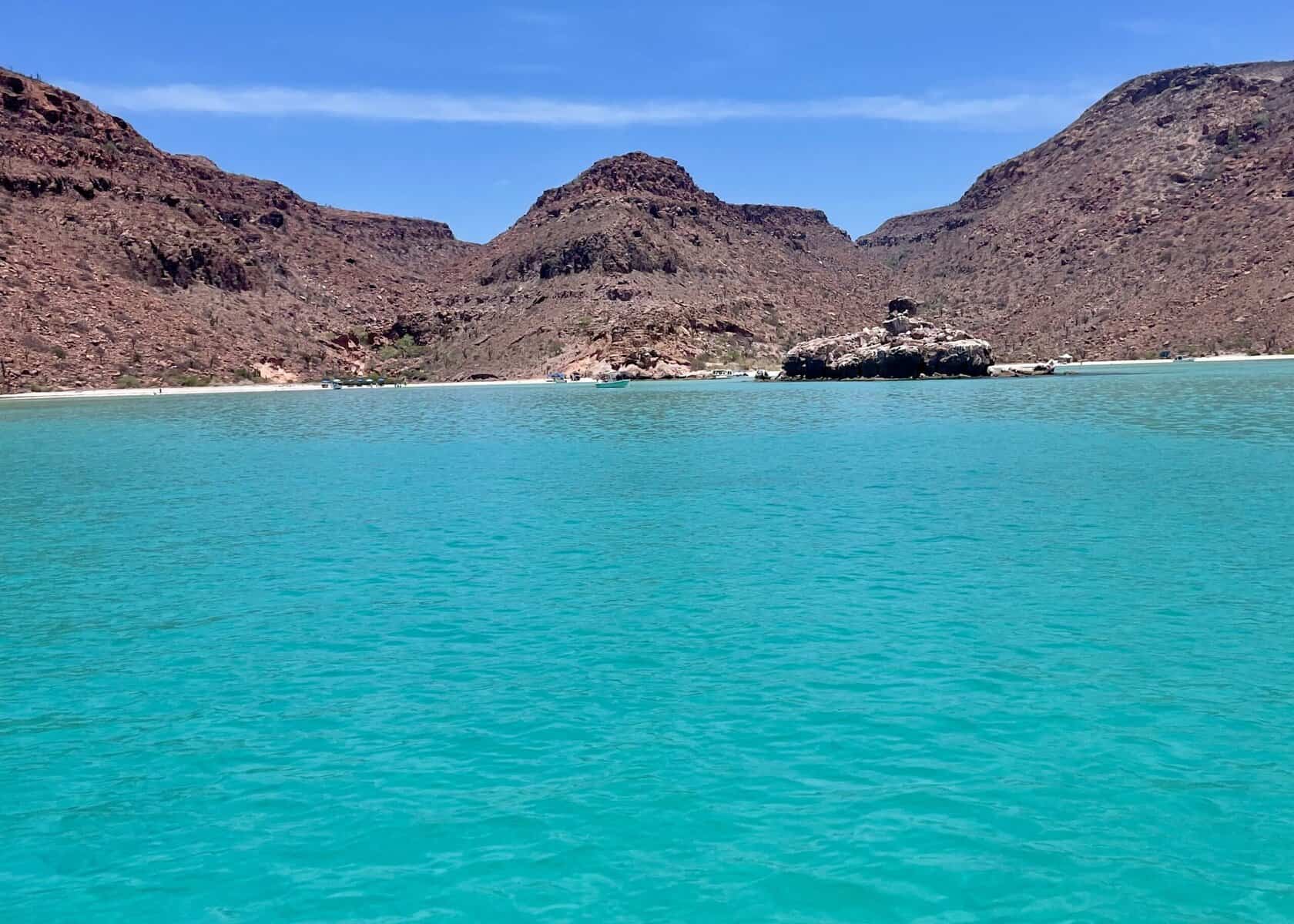 Turquoise water with a rocky, uninhabited island in the background