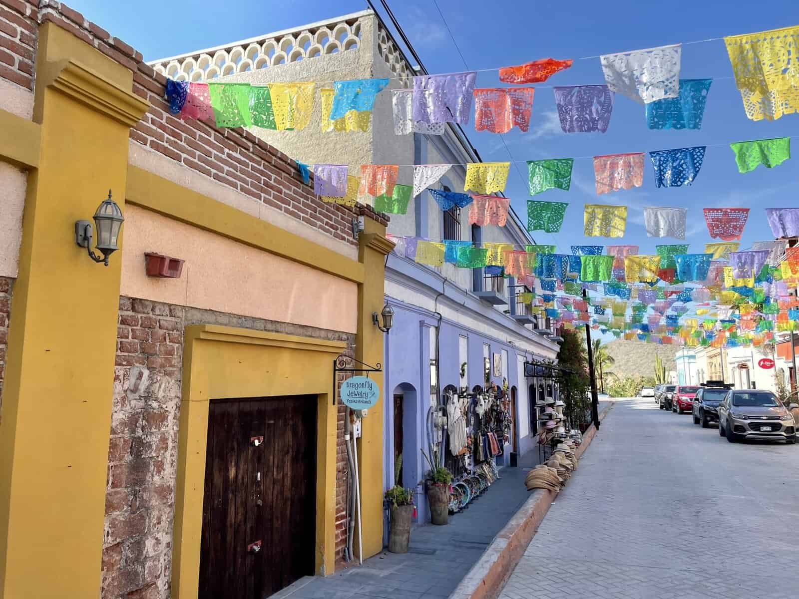 Colorful Papel Picado decorates painted buildings with a mountain in the background