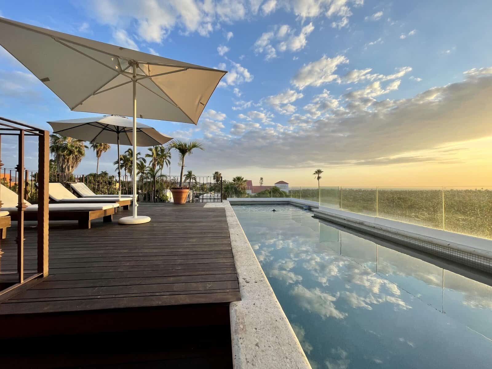 A rooftop pool reflects the clouds; the ocean can be seen in the distance