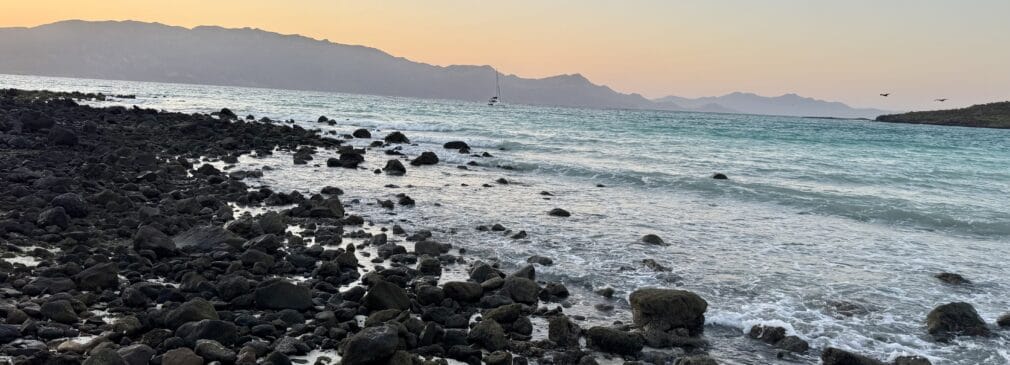 Volcanic rock on a beach with the sun setting over the ocean