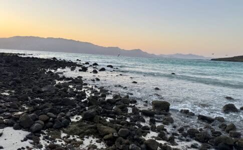 Volcanic rock on a beach with the sun setting over the ocean