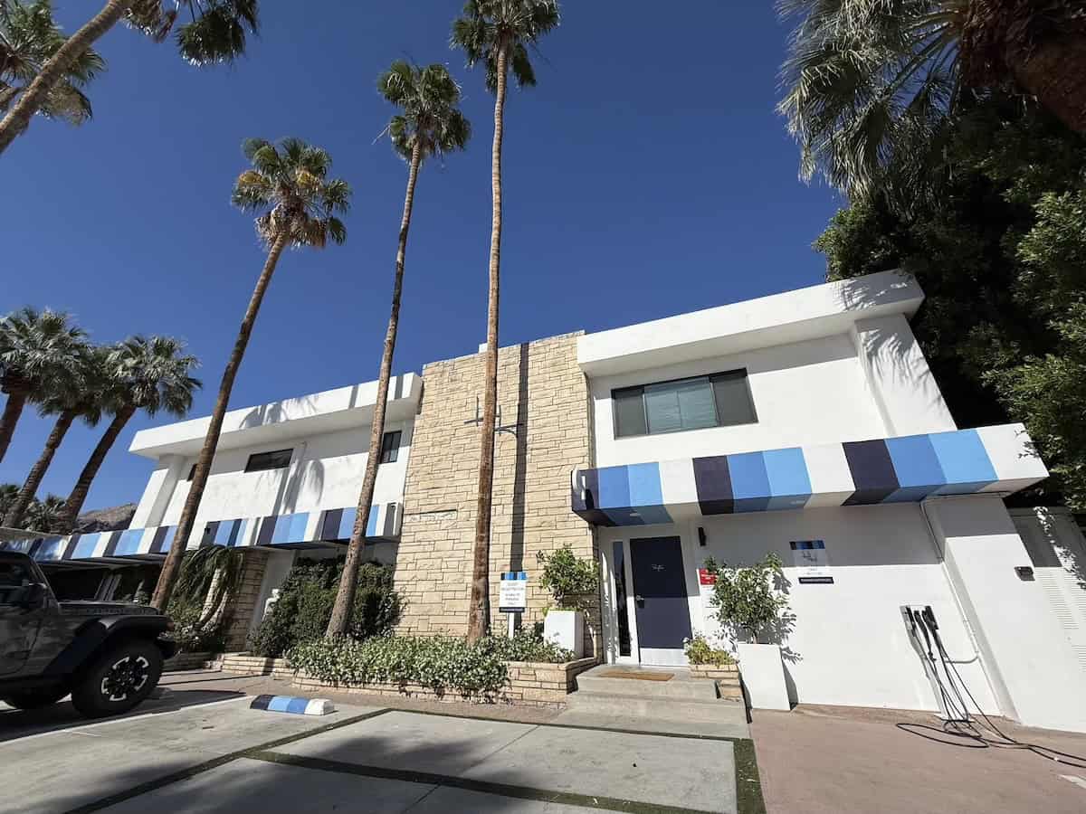 The Holiday House, a two-story midcentury modern building with white exterior, blue trim and brick accents