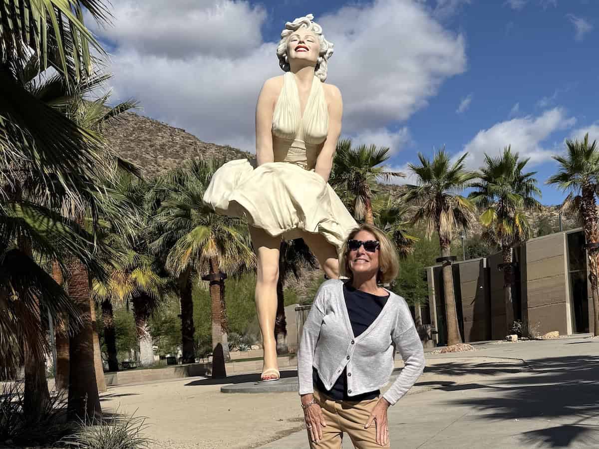 Woman beneath the Forever Marilyn Statue surrounded by palm trees. 