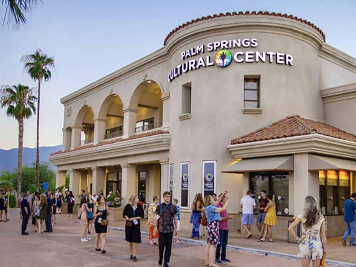 Palm Springs Cultural Center, a two-story white stucco building with arches and people gathered outside before a screening