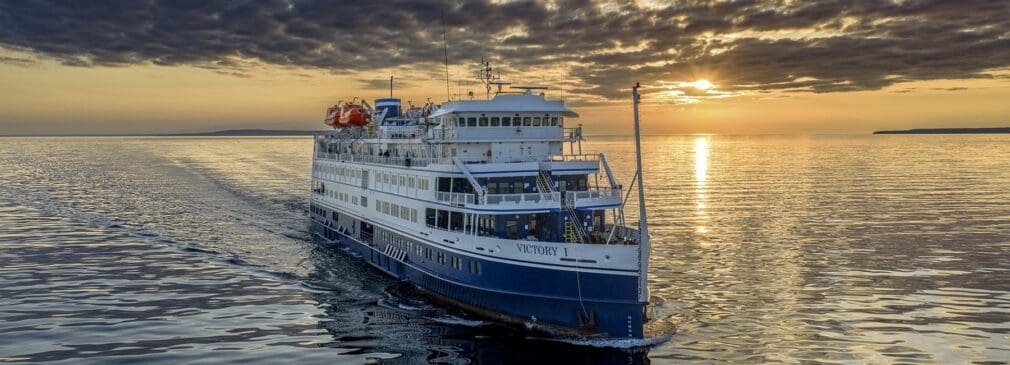 A small cruise ship on calm water at sunset.