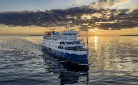 A small cruise ship on calm water at sunset.