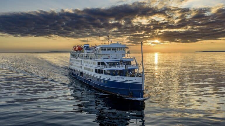 A small cruise ship on calm water at sunset.