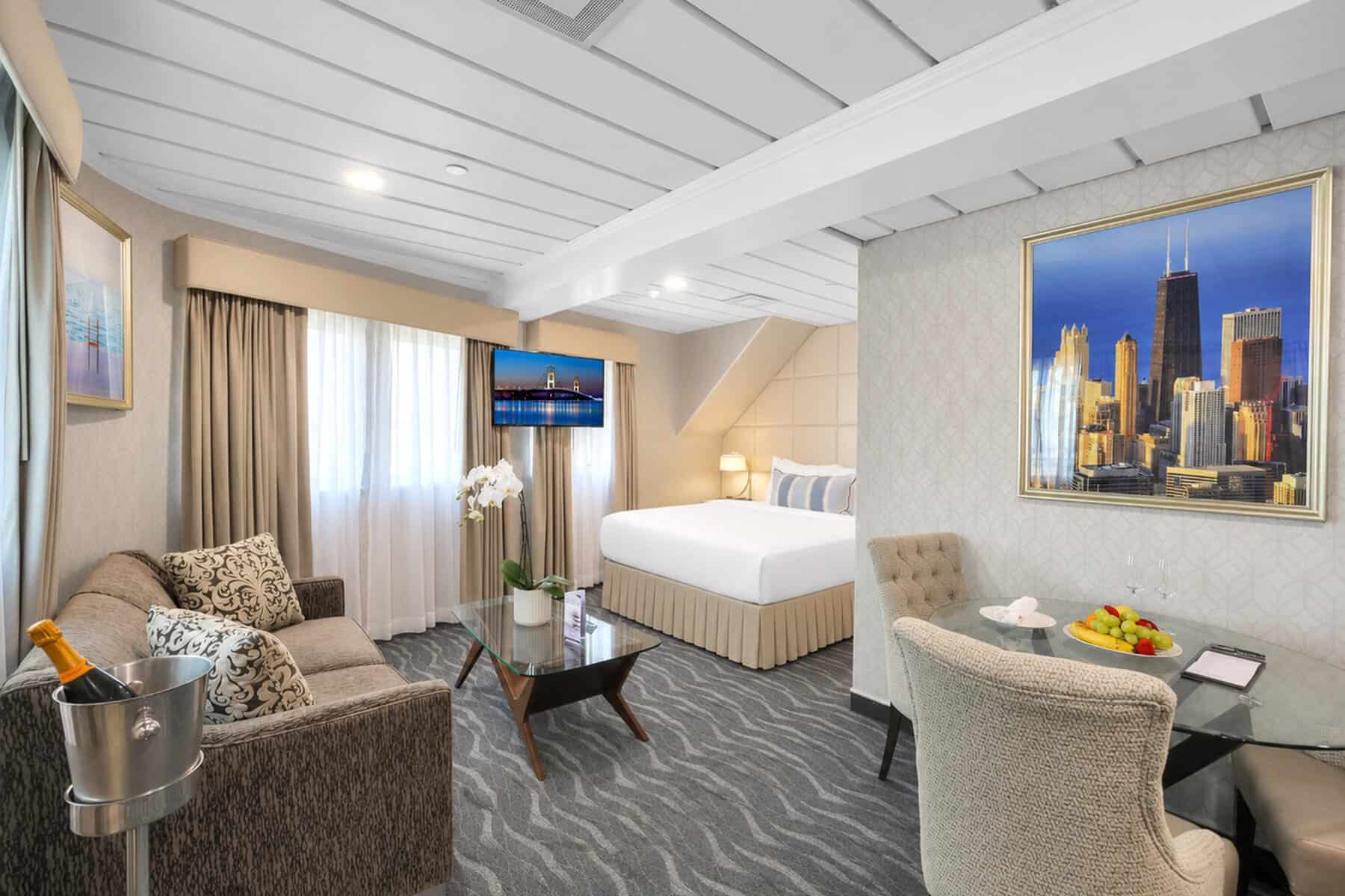  A cruise ship suite with a bed, sofa, and skyline painting.